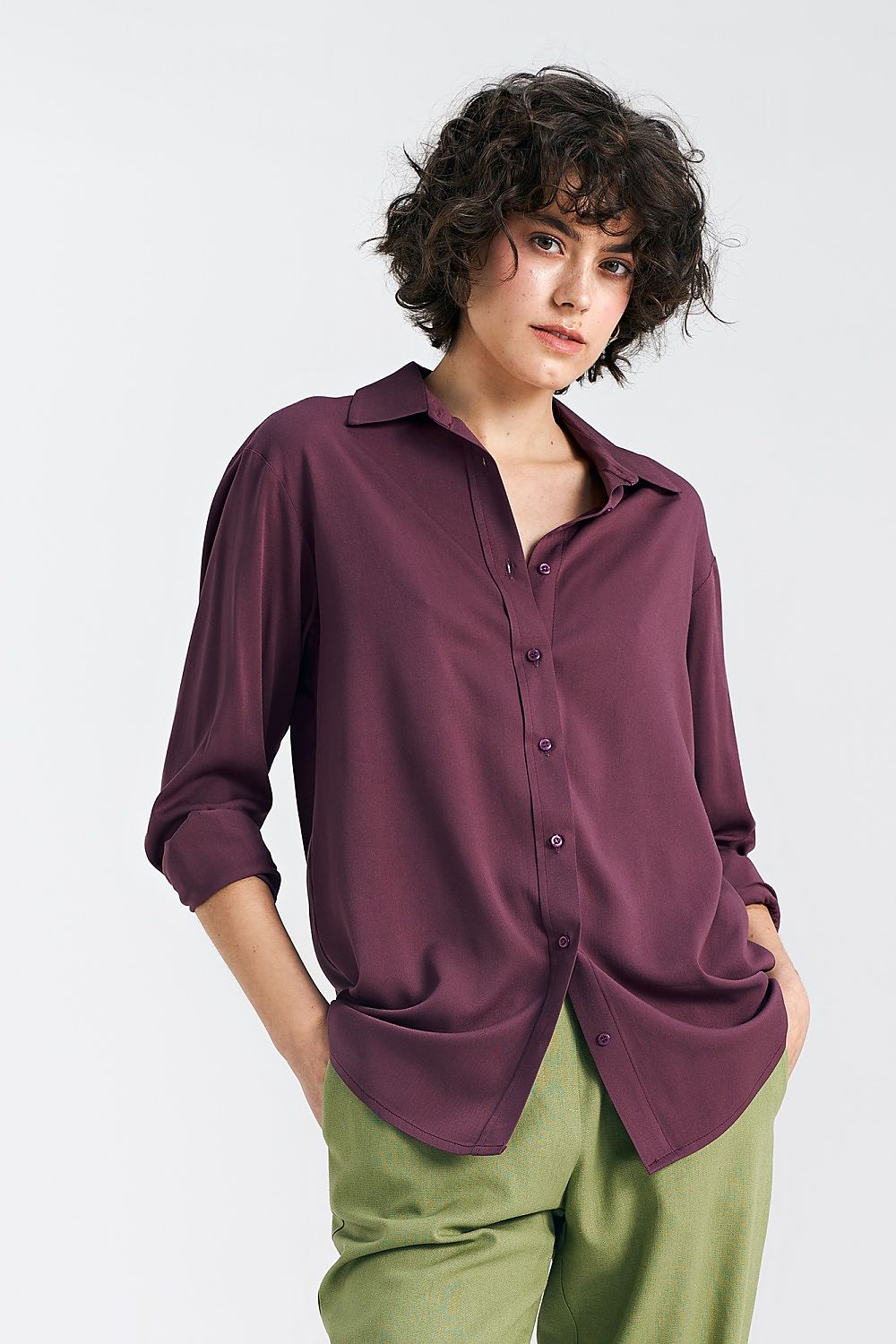 Sophisticated oversized long sleeve viscose shirt in deep plum by Nife, featuring a classic collar and button row, styled stylishly with tailored green trousers.