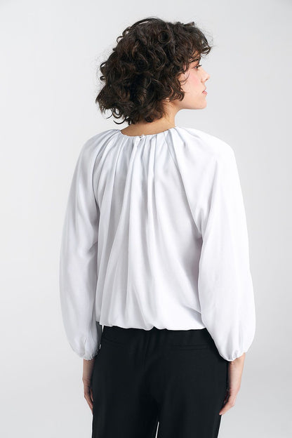 Elegant white summer blouse designed by Nife, featuring a pleated neckline and loose fit, showcasing feminine charm with a delicate ruffled hem.