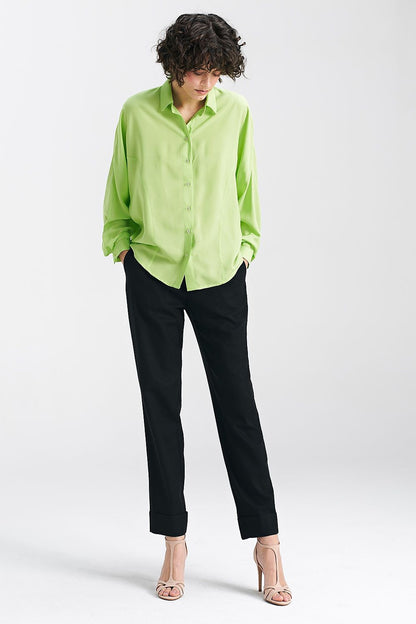 Chic lime oversize long sleeve shirt by Nife, paired with black trousers and strappy heels, emphasizing its versatility for stylish summer outfits.