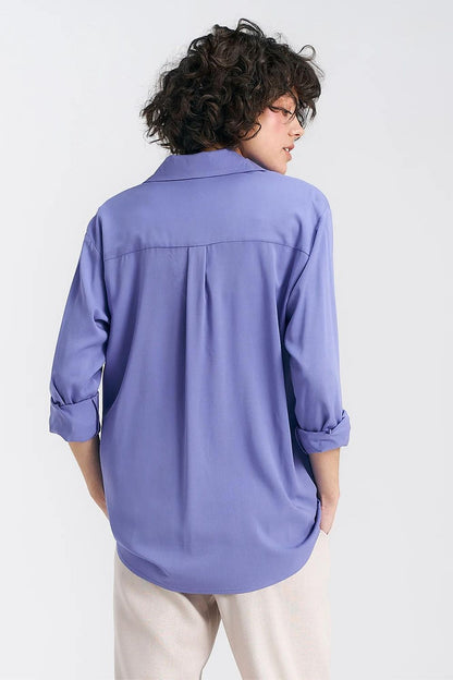 Back view of an elegant oversized long sleeve viscose shirt in lavender by Nife, highlighting the yoke detail and flowy fit, paired with cream trousers for an upscale look.