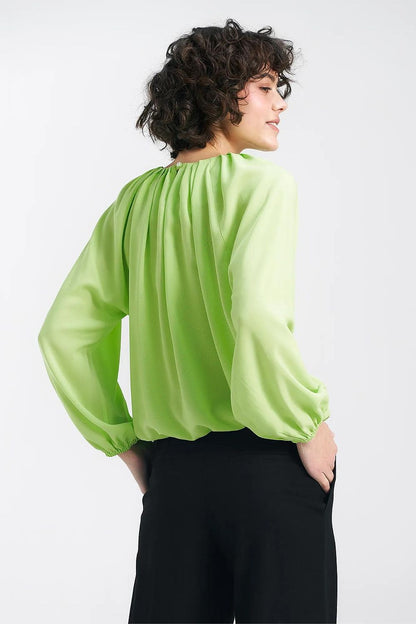Back view of the Nife lime viscose blouse, highlighting the ruffled hem and pleated detail, embodying summer elegance.