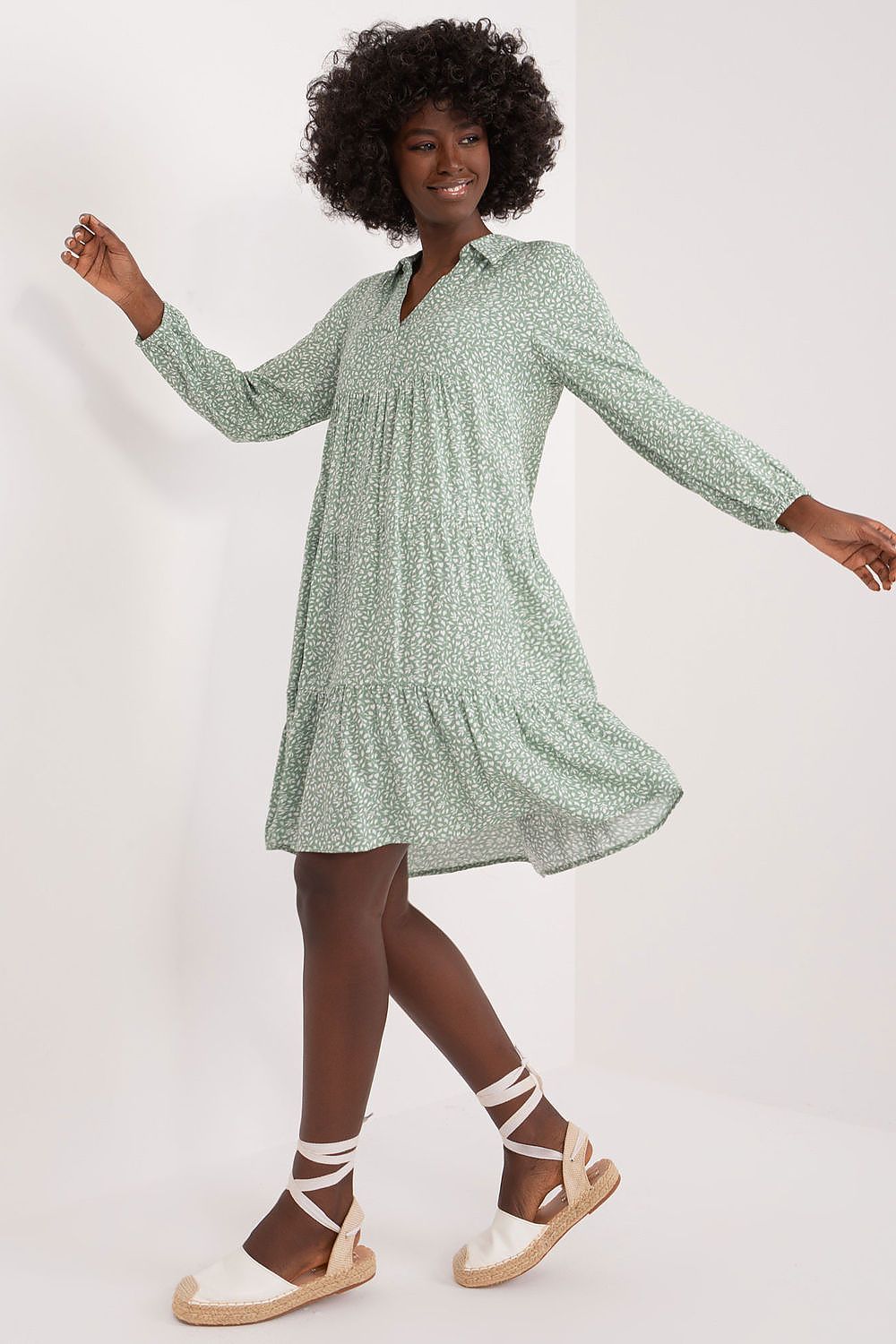 Stylish model elegantly wearing a relaxed oversized summer dress by Sublevel in lightweight viscose, featuring a distinctive green print and flowing ruffle hem, suitable for summer elegance.