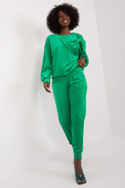 Stylish woman in luxurious green velour two-piece sweatshirt and pants set by Italy Moda, featuring feminine bow detail and elegant design, showcasing comfort and contemporary style.