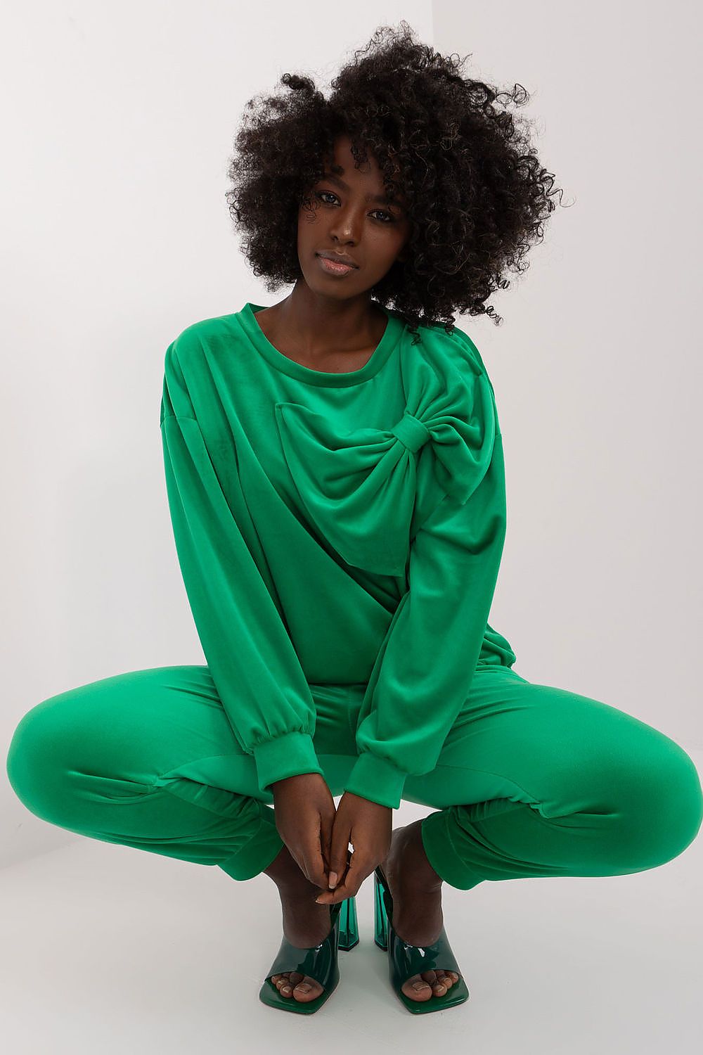 Chic model posing in vibrant green velour outfit by Italy Moda, featuring a sophisticated bow detail on the sweatshirt, exuding a modern and fashionable appearance.