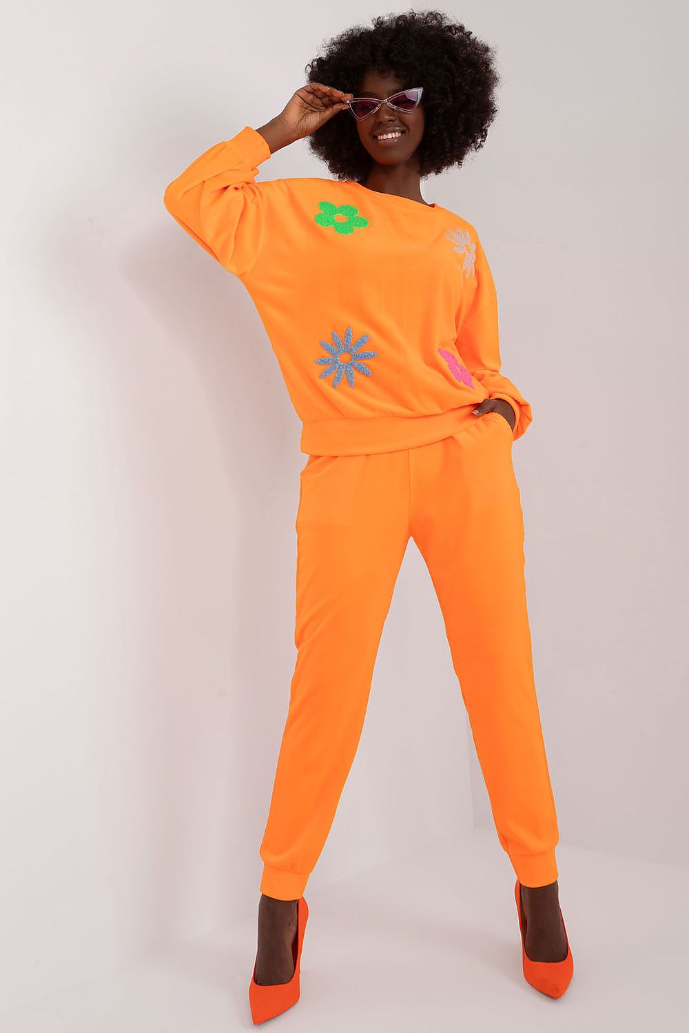 Stylish long sleeve floral print velour set by Italy Moda, featuring a vibrant orange sweatshirt with floral appliqué and matching high-waisted pants, perfect for a chic casual look.