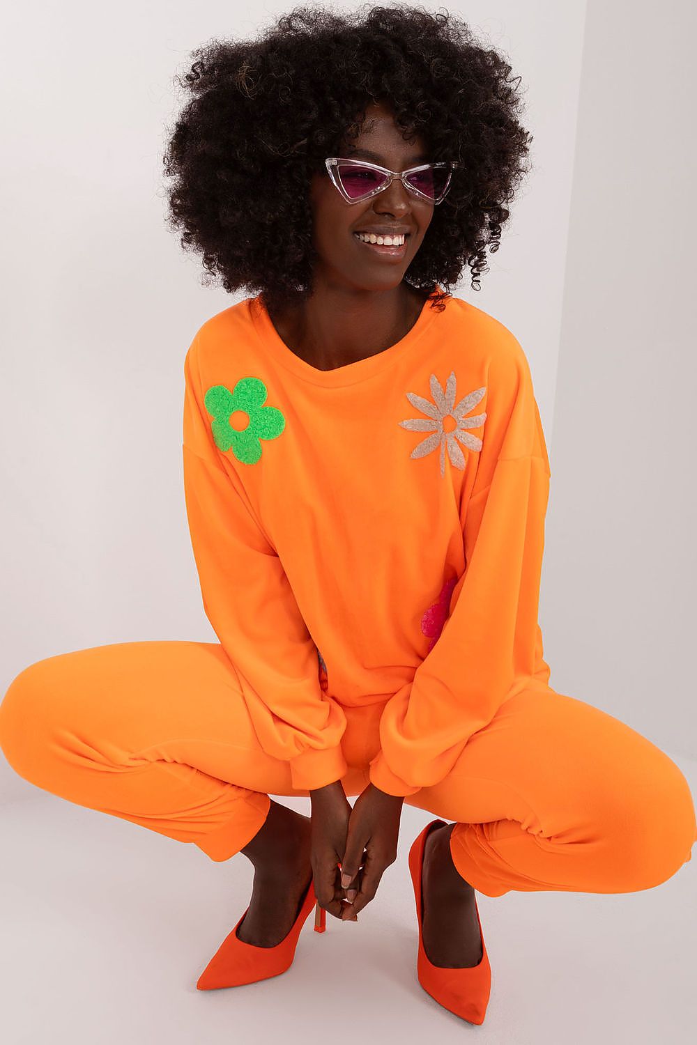 Chic orange velour set by Italy Moda, showcasing a relaxed fit sweatshirt adorned with floral designs and high-waisted pants, ideal for elegant summer evenings.