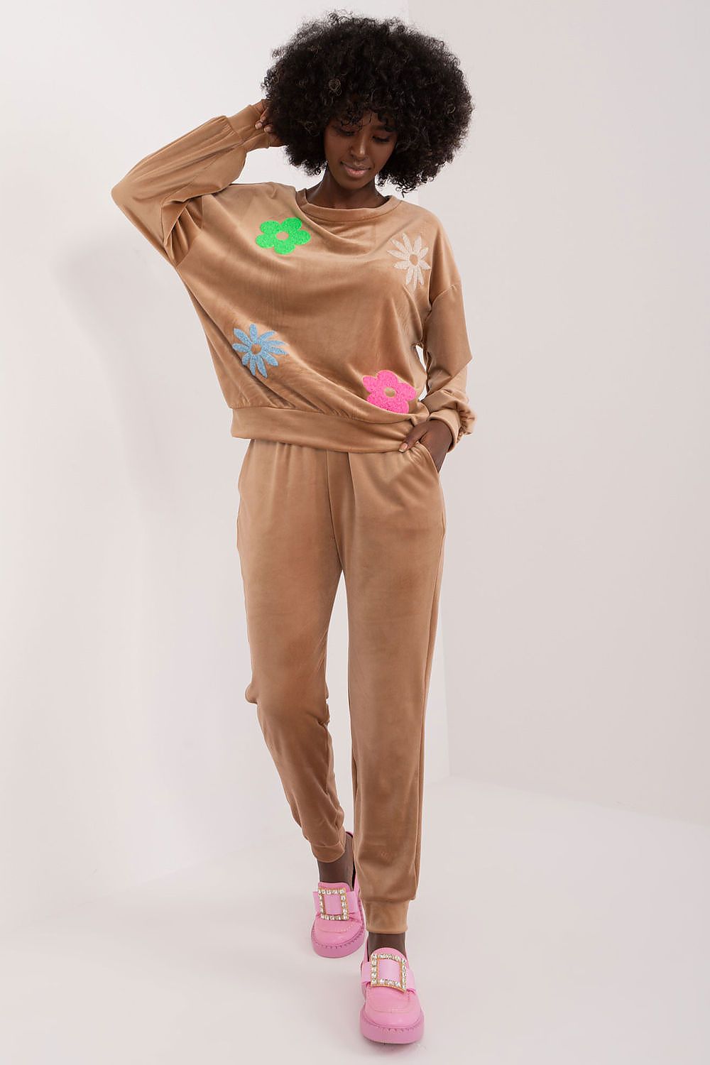 Model elegantly displaying the luxurious brown floral velour set by Italy Moda, featuring a chic long-sleeve sweatshirt with vibrant floral appliqués, perfectly paired with high-waisted trousers and stylish pink chunky shoes for a striking casual outfit.