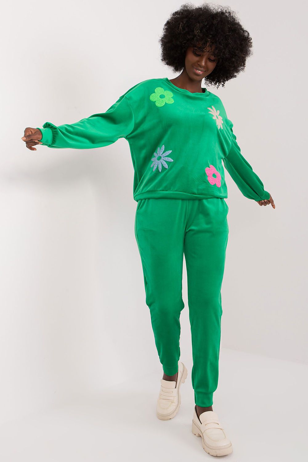 Elegant green velour set featuring long sleeve sweatshirt and high waisted pants with floral embellishments, modelled by a woman, by Italy Moda.