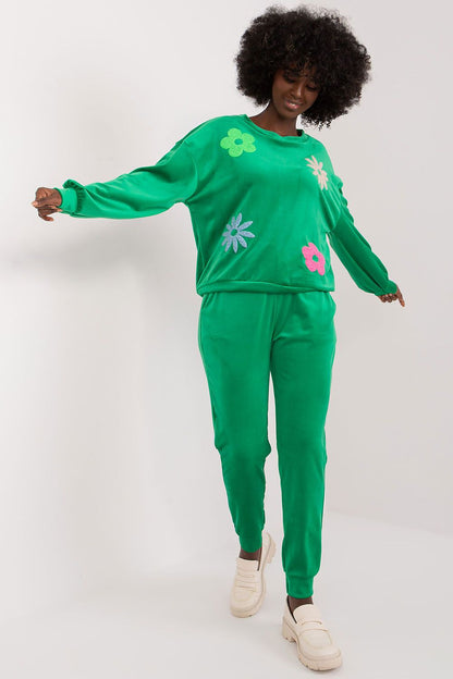 Elegant green velour set featuring long sleeve sweatshirt and high waisted pants with floral embellishments, modelled by a woman, by Italy Moda.