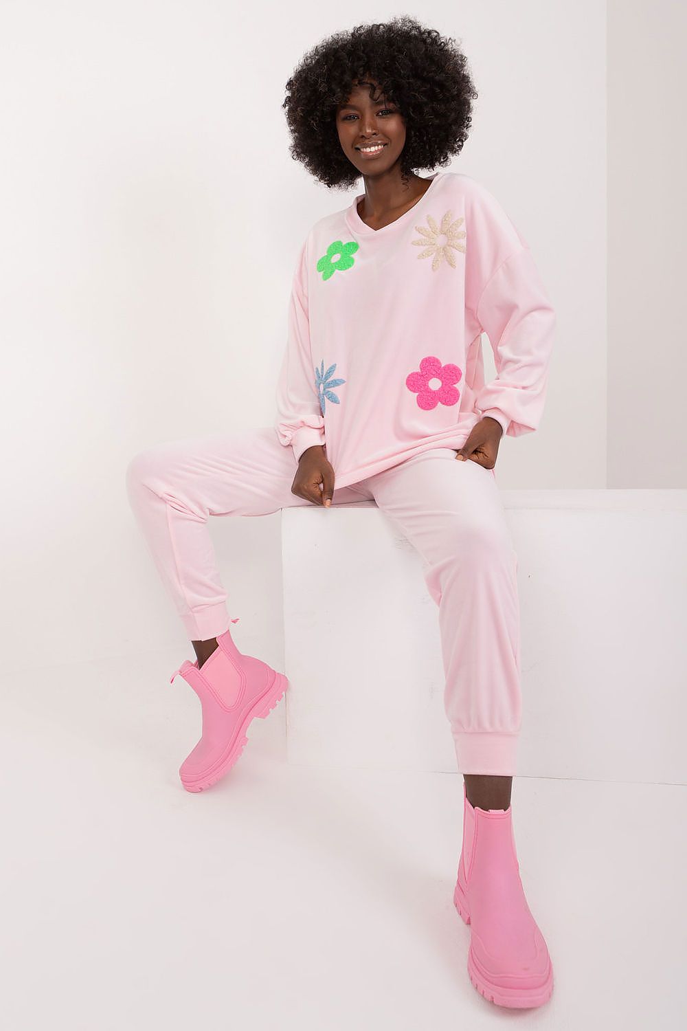 Trendy pink velour ensemble featuring long sleeve floral sweatshirt and high waisted pants, elegantly modelled, by Italy Moda.