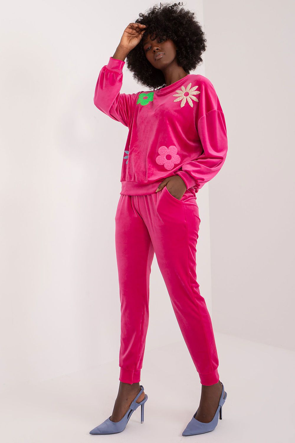 Sophisticated pink velour set from Italy Moda, featuring a stylish floral design on the sweatshirt. Model presents a modern and elegant ensemble, ideal for relaxed summer evenings.