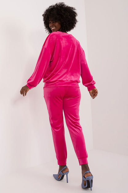 Chic and comfortable pink velour set by Italy Moda, highlighted by playful floral appliques. The model poses elegantly, showcasing the high-waisted pants that perfectly accentuate her silhouette.