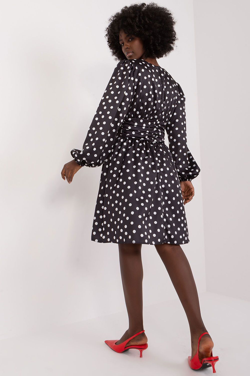 A stylish view of the back of a cocktail dress by Lakerta, highlighting its beautiful design with puff sleeves and a charming waistline. The polka dot pattern stands out elegantly, complemented by red slingback heels for a luxurious finish.