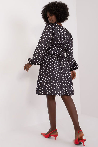 A stylish view of the back of a cocktail dress by Lakerta, highlighting its beautiful design with puff sleeves and a charming waistline. The polka dot pattern stands out elegantly, complemented by red slingback heels for a luxurious finish.