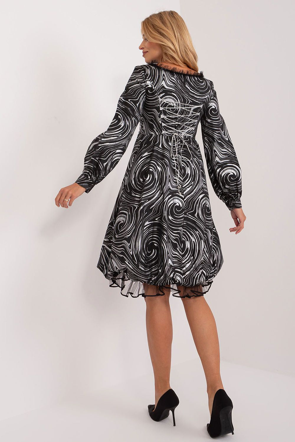 Elegant Lakerta evening dress featuring a unique swirling black and white print, flared cut, and long buff sleeves, showcased from the back.