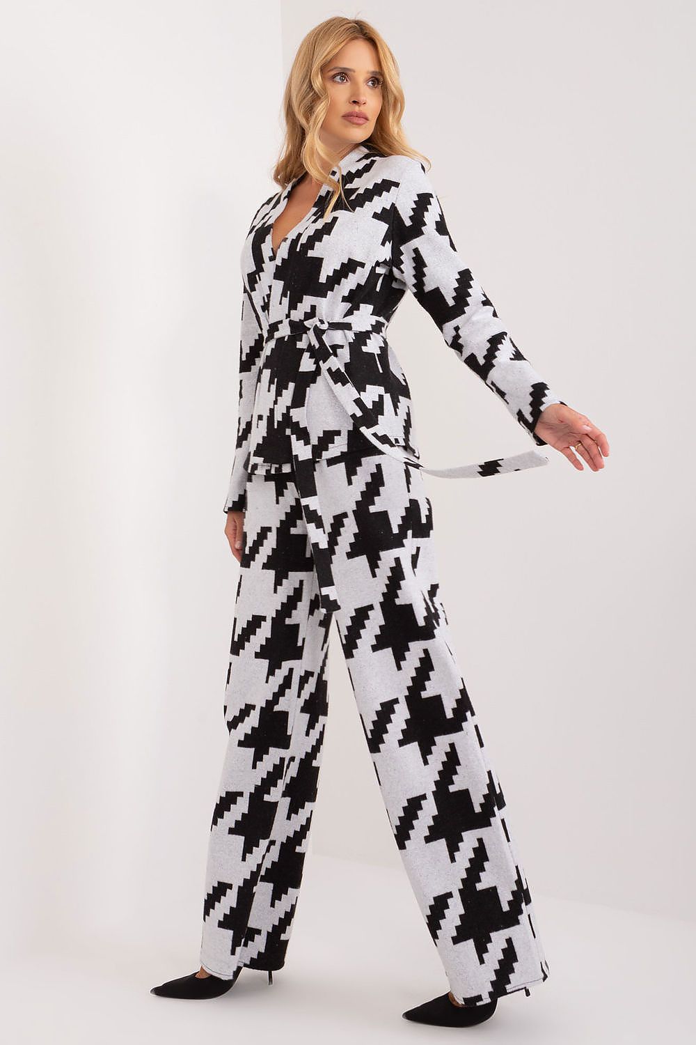 Side view of the Lakerta cotton sweater and pants set in a bold peplite pattern. The model showcases the outfit's versatility and elegant silhouette, featuring long sleeves and a stylish tie belt.
