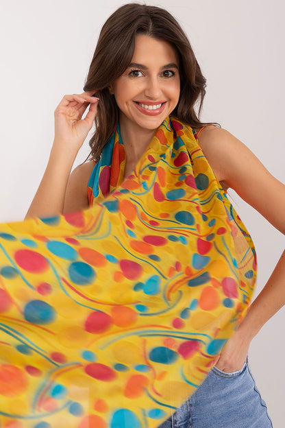Elegant model showcasing a vibrant luxury neckerchief by AT, featuring a unique print with colourful patterns, made from 100% cotton. The neckerchief has dimensions of 184 cm in length and 70 cm in width.