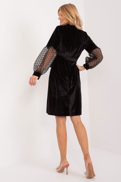 Side view of Lakerta's elegant knee-length dress, highlighting the flattering silhouette and transparent sleeves that enhance elegance and femininity.