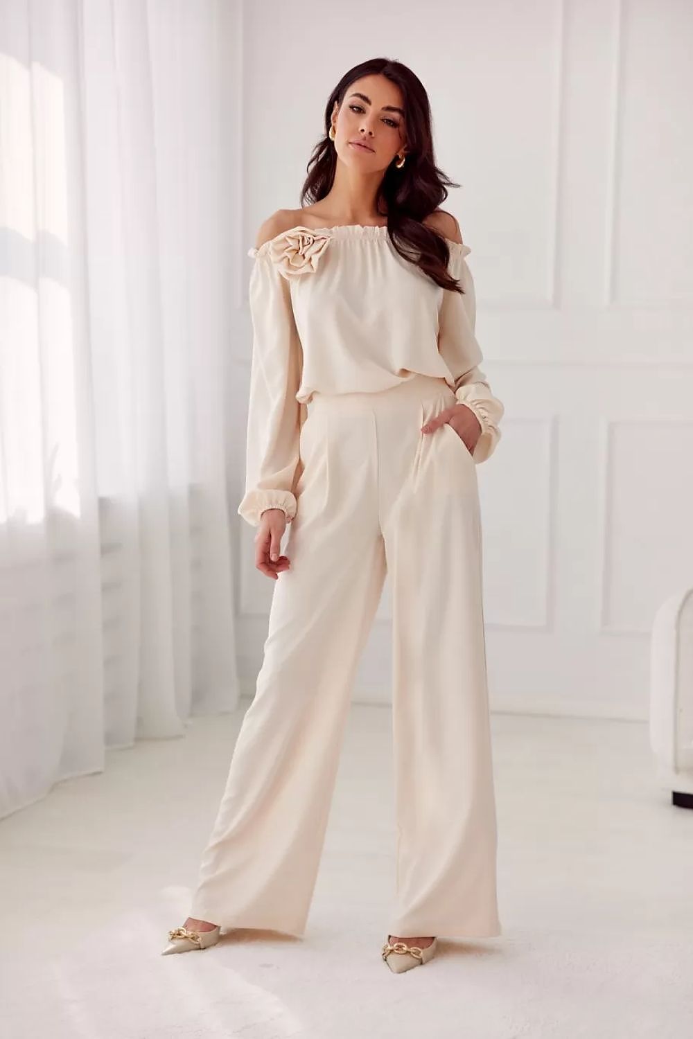 Model wearing the Rosie Satin Blouse by Roco Fashion, exemplifying elegance with the Spanish neckline and styled with formal trousers.