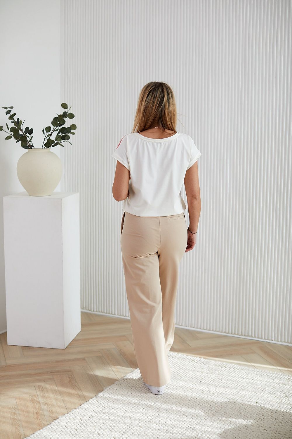 Stylish model wearing a La Aurora luxurious cotton knit blouse with a lively fruit design and shimmering rhinestones, a statement piece for sophisticated wardrobes.