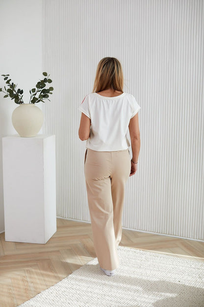 Stylish model wearing a La Aurora luxurious cotton knit blouse with a lively fruit design and shimmering rhinestones, a statement piece for sophisticated wardrobes.