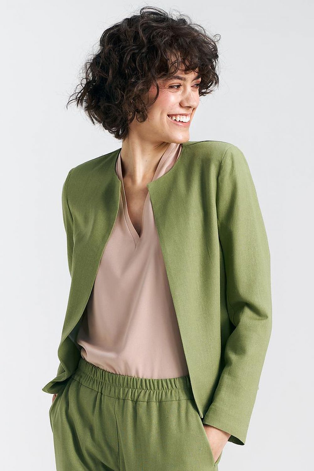 Elegant pistachio green boxy jacket by Nife, model showcasing a refined style with soft curls and a sophisticated expression, complementing luxurious fabric.