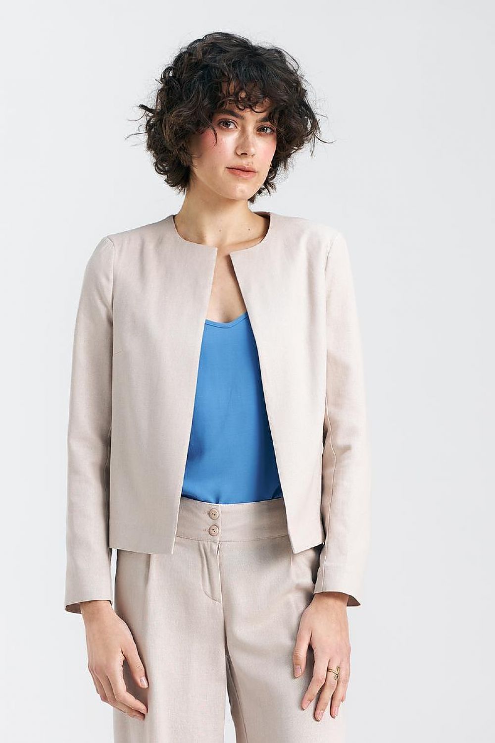 Sophisticated model wearing a beige boxy jacket paired with a vibrant blue top, showcasing the elegant design of Nife's collection.
