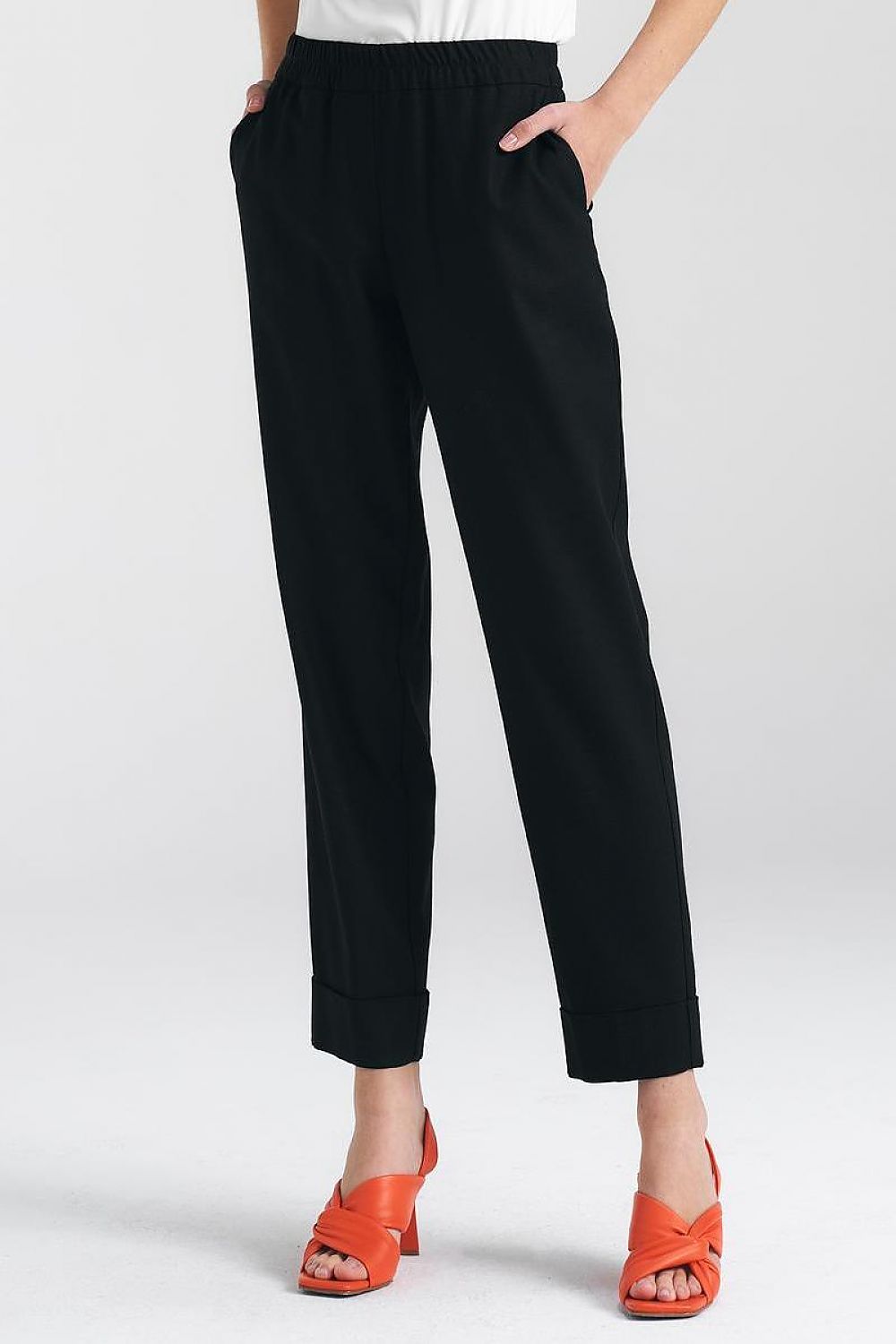 Chic black trousers by Nife featuring a relaxed fit and elegant cuffs, complemented with vibrant orange heels for a stylish ensemble.