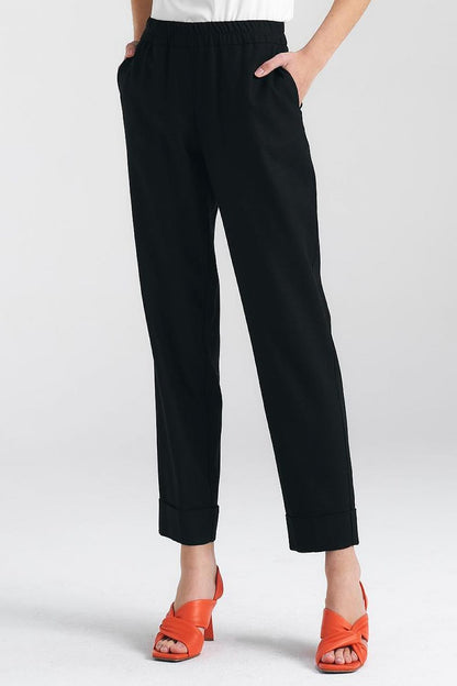 Chic black trousers by Nife featuring a relaxed fit and elegant cuffs, complemented with vibrant orange heels for a stylish ensemble.