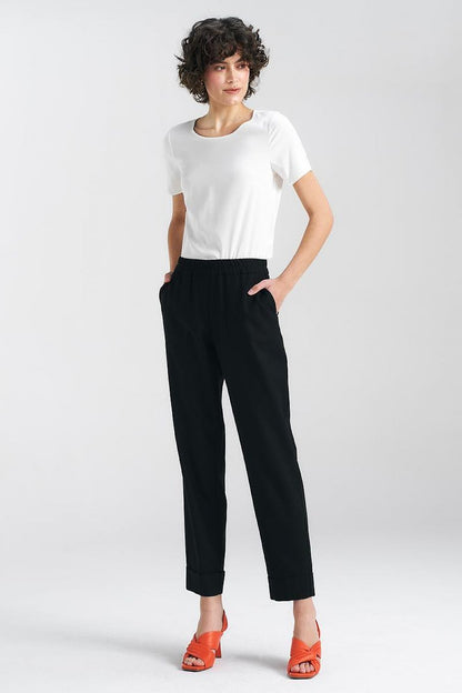 Versatile black trousers by Nife with a relaxed silhouette, paired with a classic white top and orange heels, perfect for both casual and smart-casual occasions.