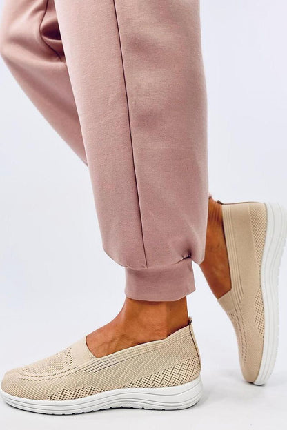 Sophisticated Inello slip-on sneakers for women, designed with breathable fabric and a sleek profile, displayed on a model in casual pink joggers.
