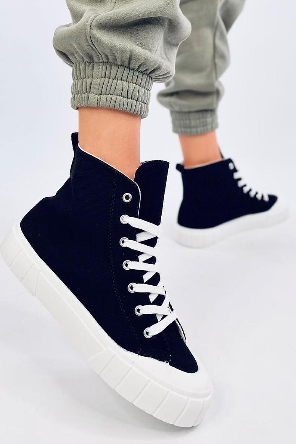 Chic black women's canvas ankle sneakers by Inello, showcasing a thick white sole, worn in a stylish outfit with joggers, highlighting the trendy design and comfort.