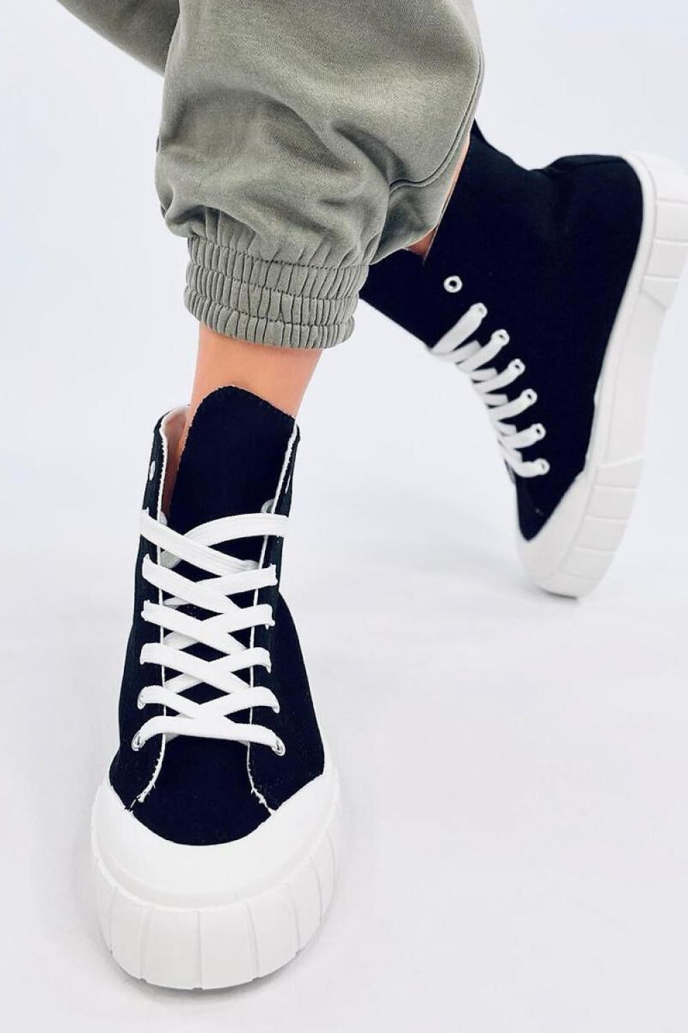Stylish women's black canvas ankle sneakers by Inello, featuring a thick white sole, captured in a modern setting. Perfect for adding a fashionable touch to your outfit.