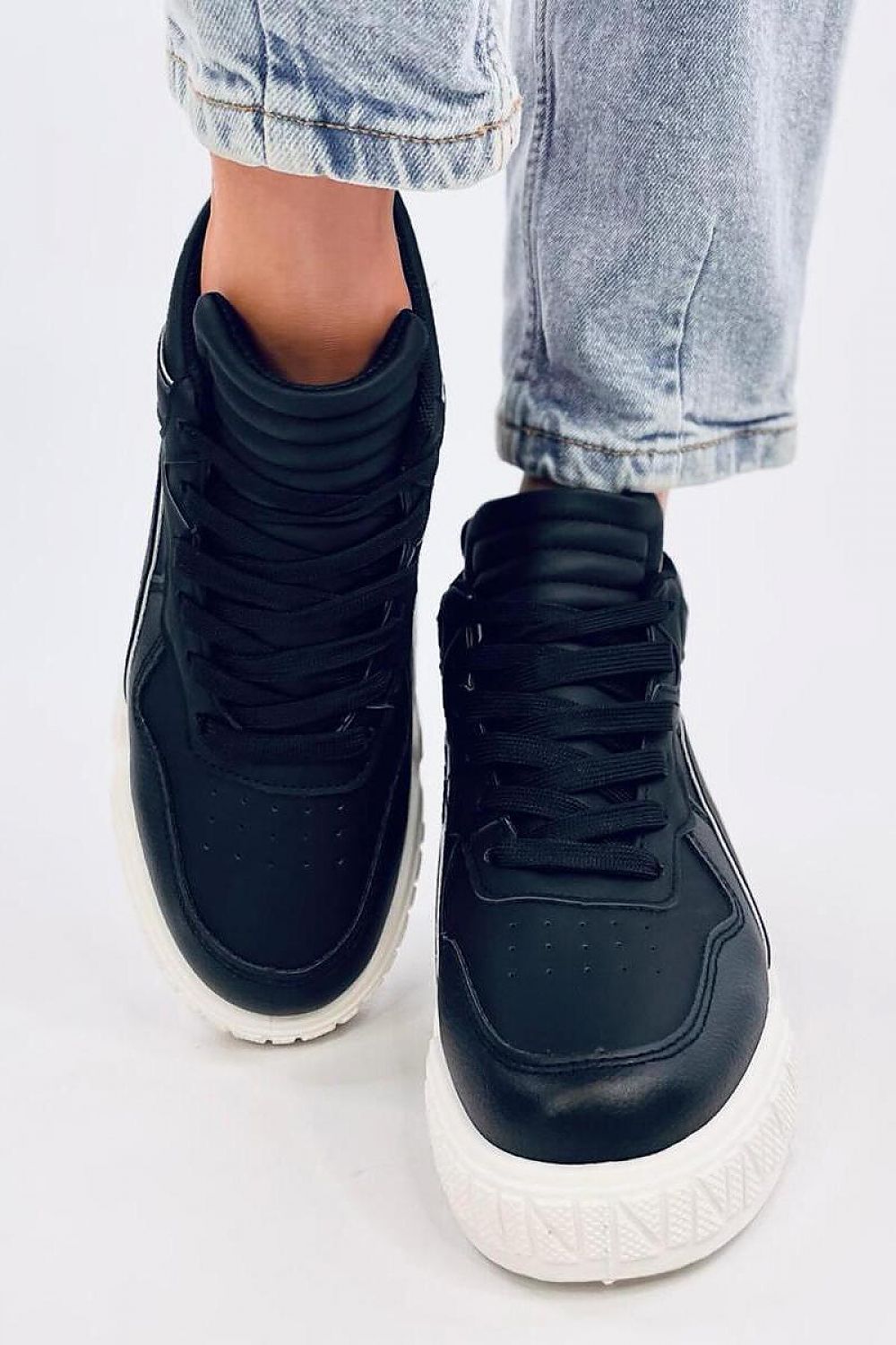 Inello women's black lace-up sneakers worn with denim, highlighting the comfort and stylish appeal of these eco-friendly footwear options.