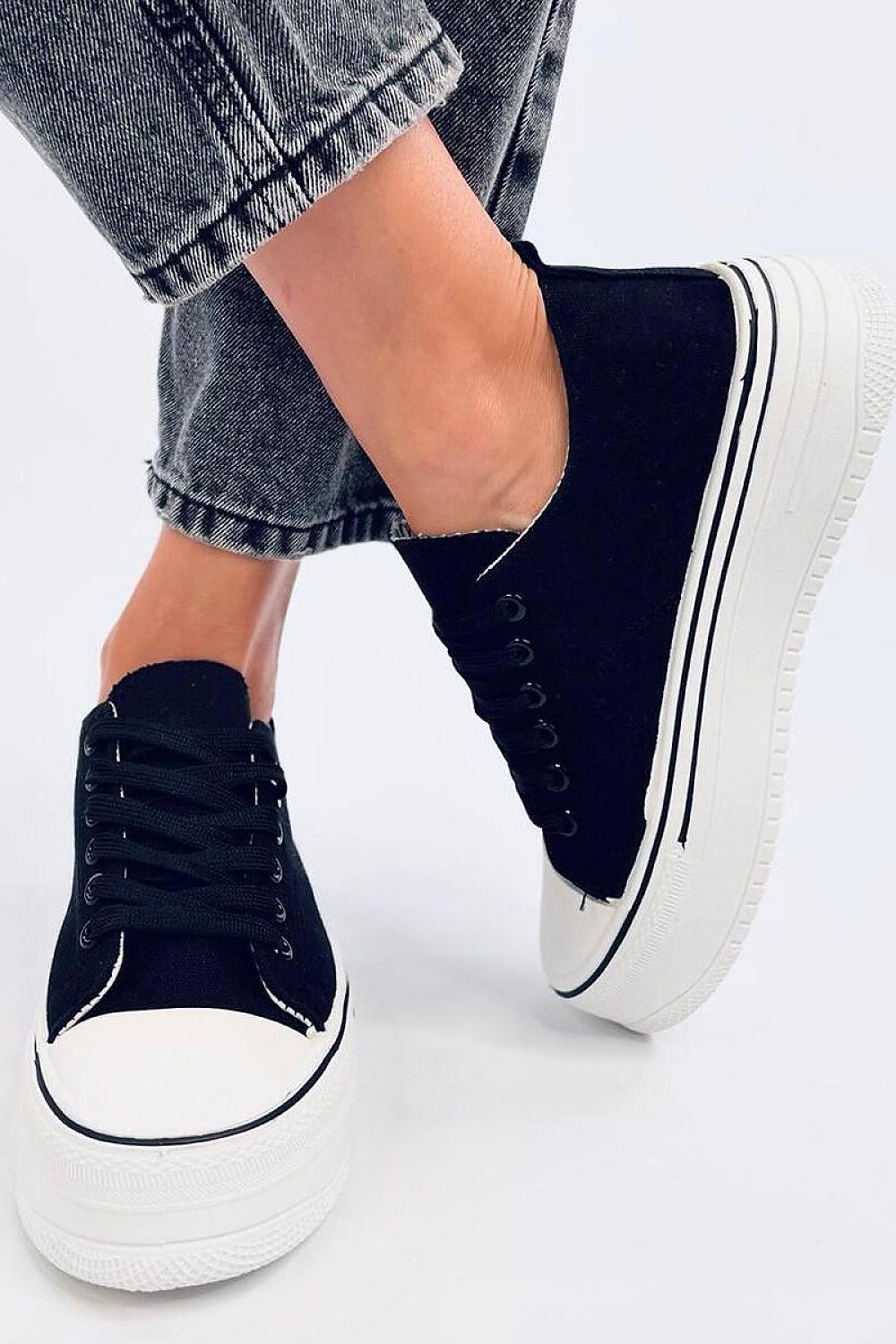 Elegant black platform sneakers by Inello worn with denim, featuring a fashionable high sole for a perfect blend of comfort and style.