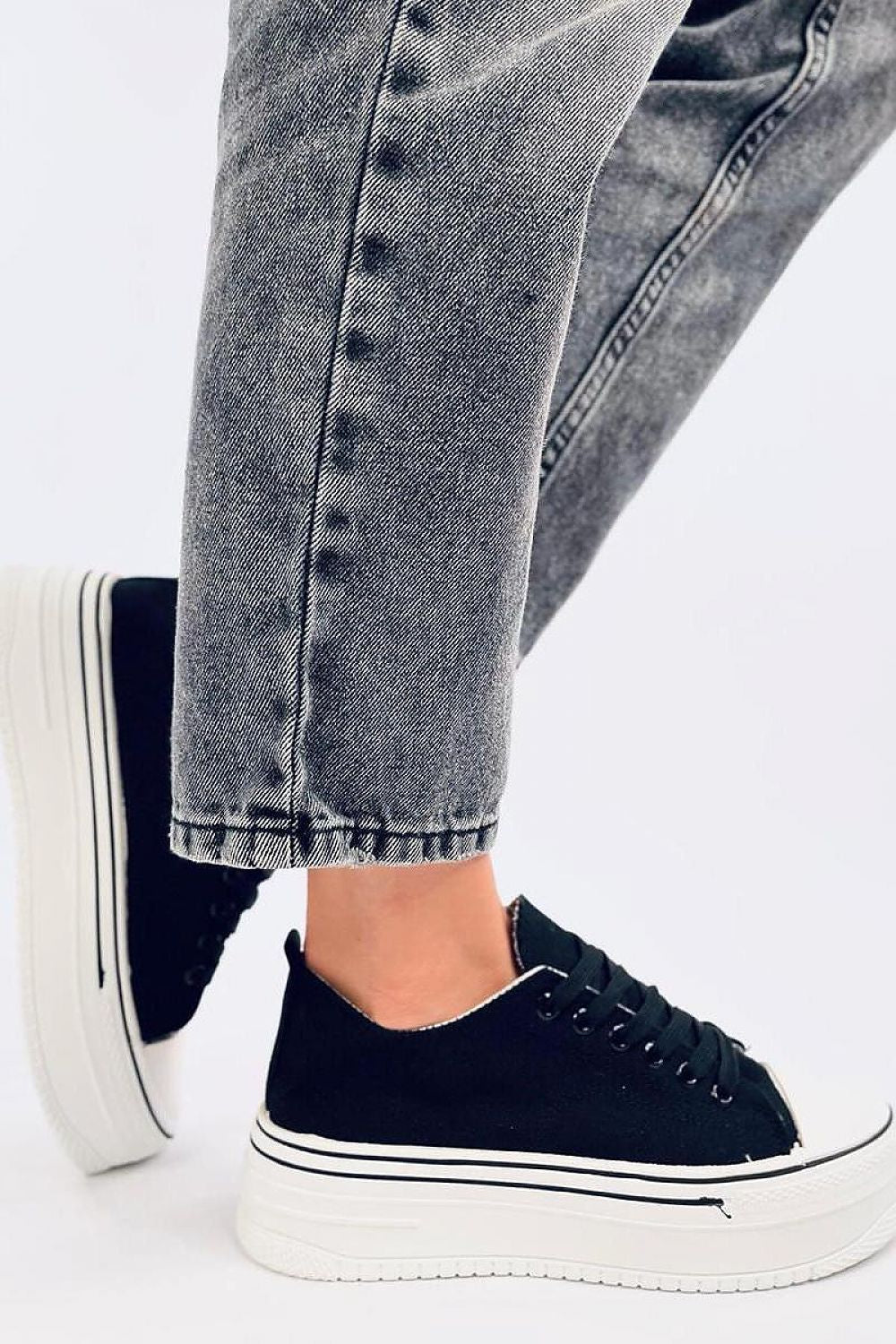 Luxury women's black platform sneakers by Inello, featuring a high sole and trendy design, paired with denim trousers for a stylish look.
