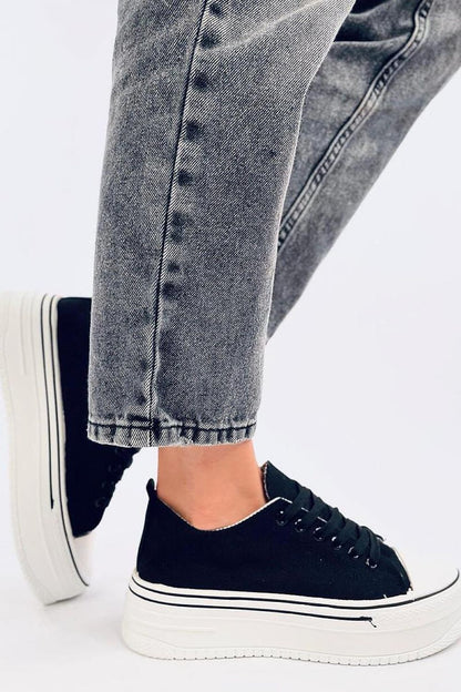 Luxury women's black platform sneakers by Inello, featuring a high sole and trendy design, paired with denim trousers for a stylish look.