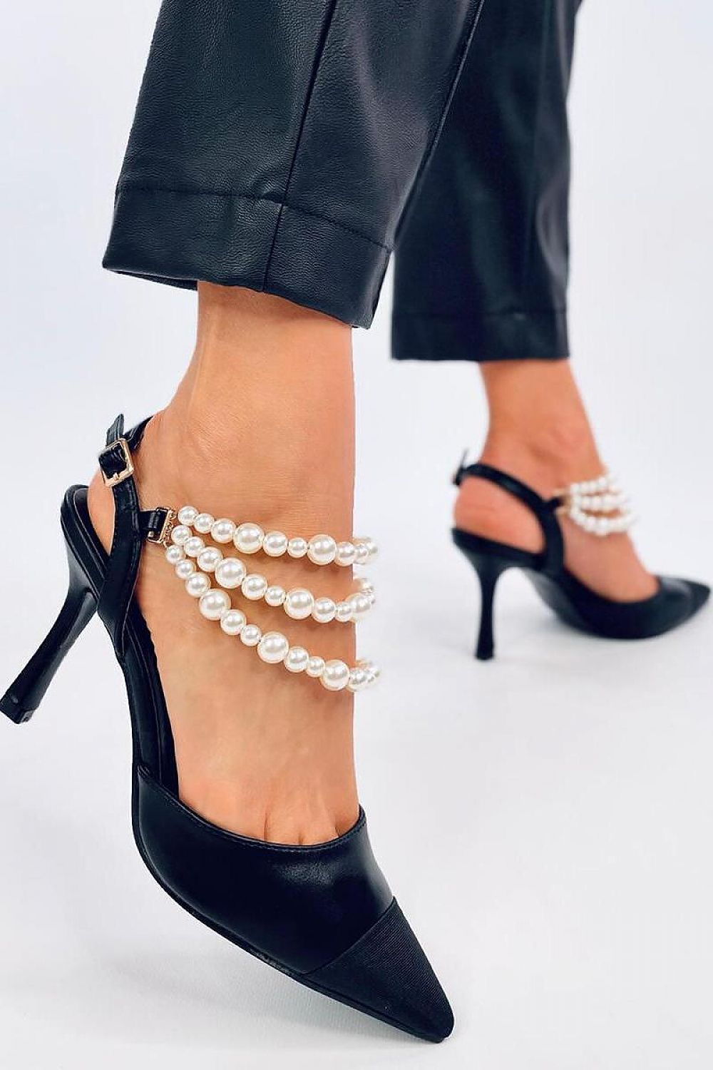 Sophisticated black stilettos by Inello, adorned with cascading pearl accents, elegantly displayed on a woman's foot.