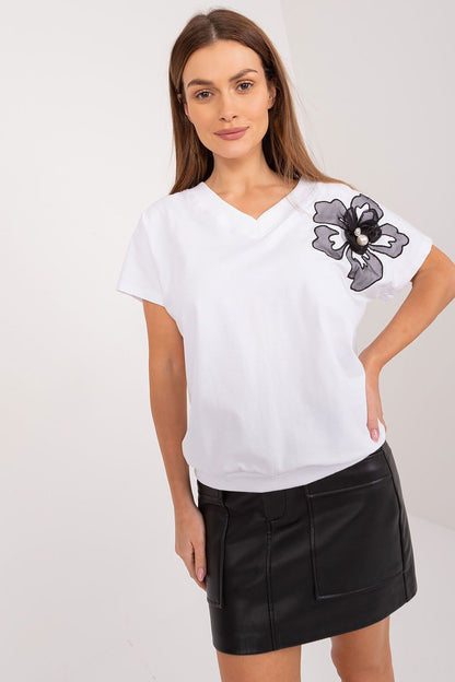 Chic woman modelling an elegant white cotton blouse with a black floral design and zircon detail, paired with a stylish leather skirt, by BFG.
