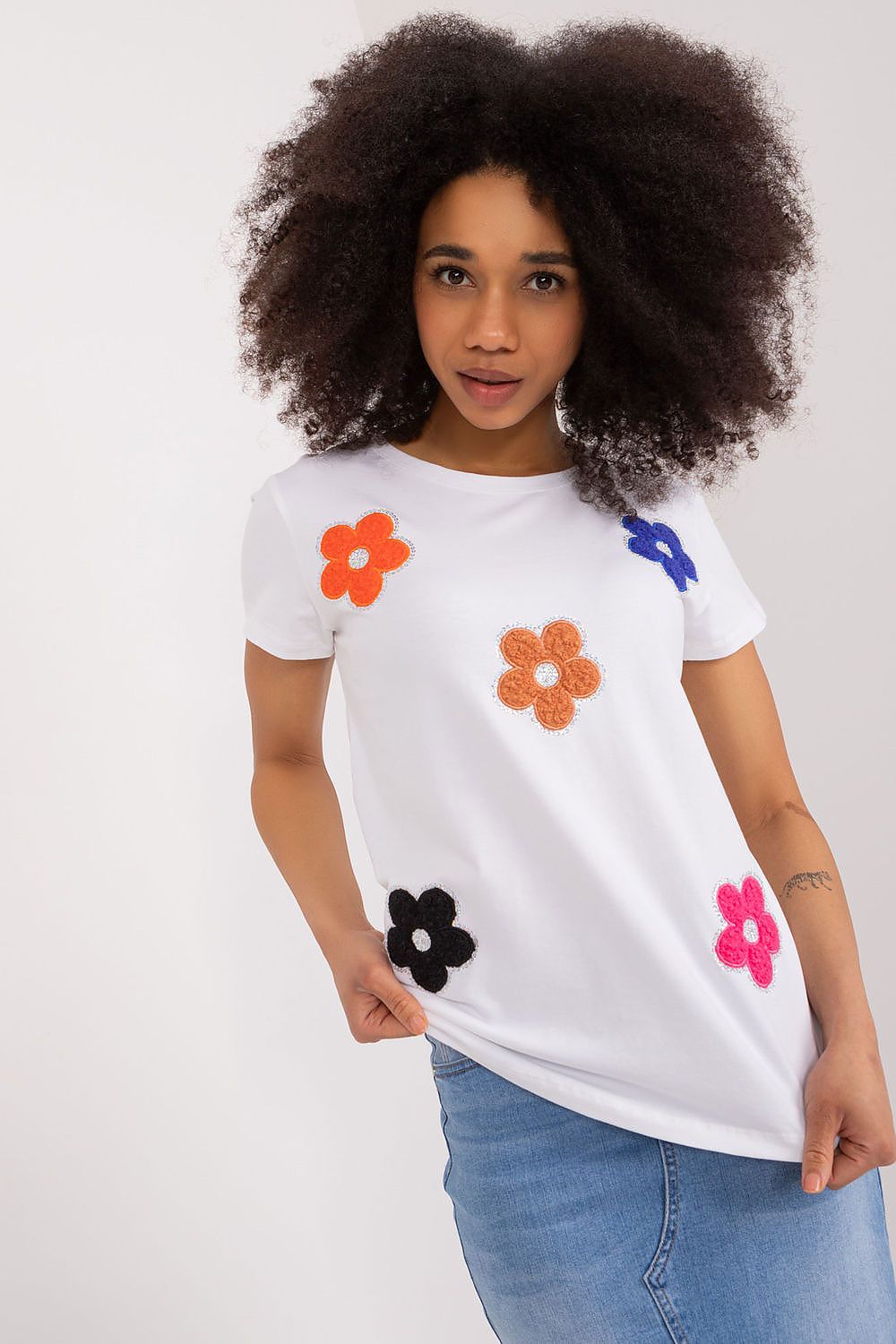 Elegant white cotton blouse adorned with colourful floral decorations, modelled by a woman, by BFG.