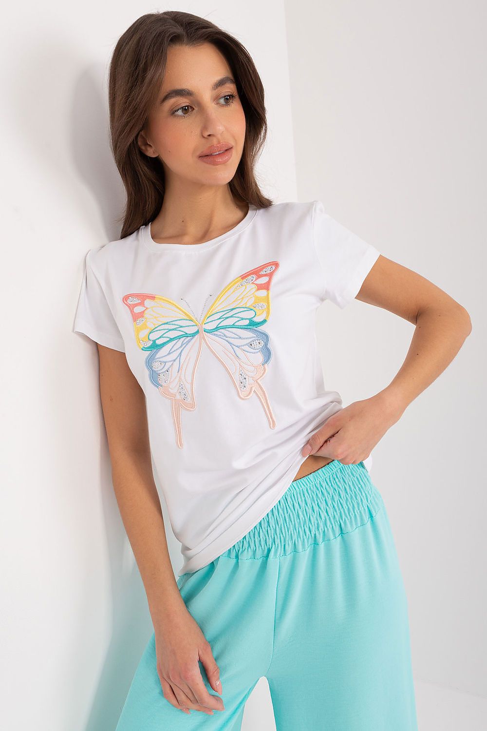 Charming model wearing a white BFG casual cotton blouse adorned with an artistic butterfly design, accentuating the allure and sophistication suitable for leisure outings.