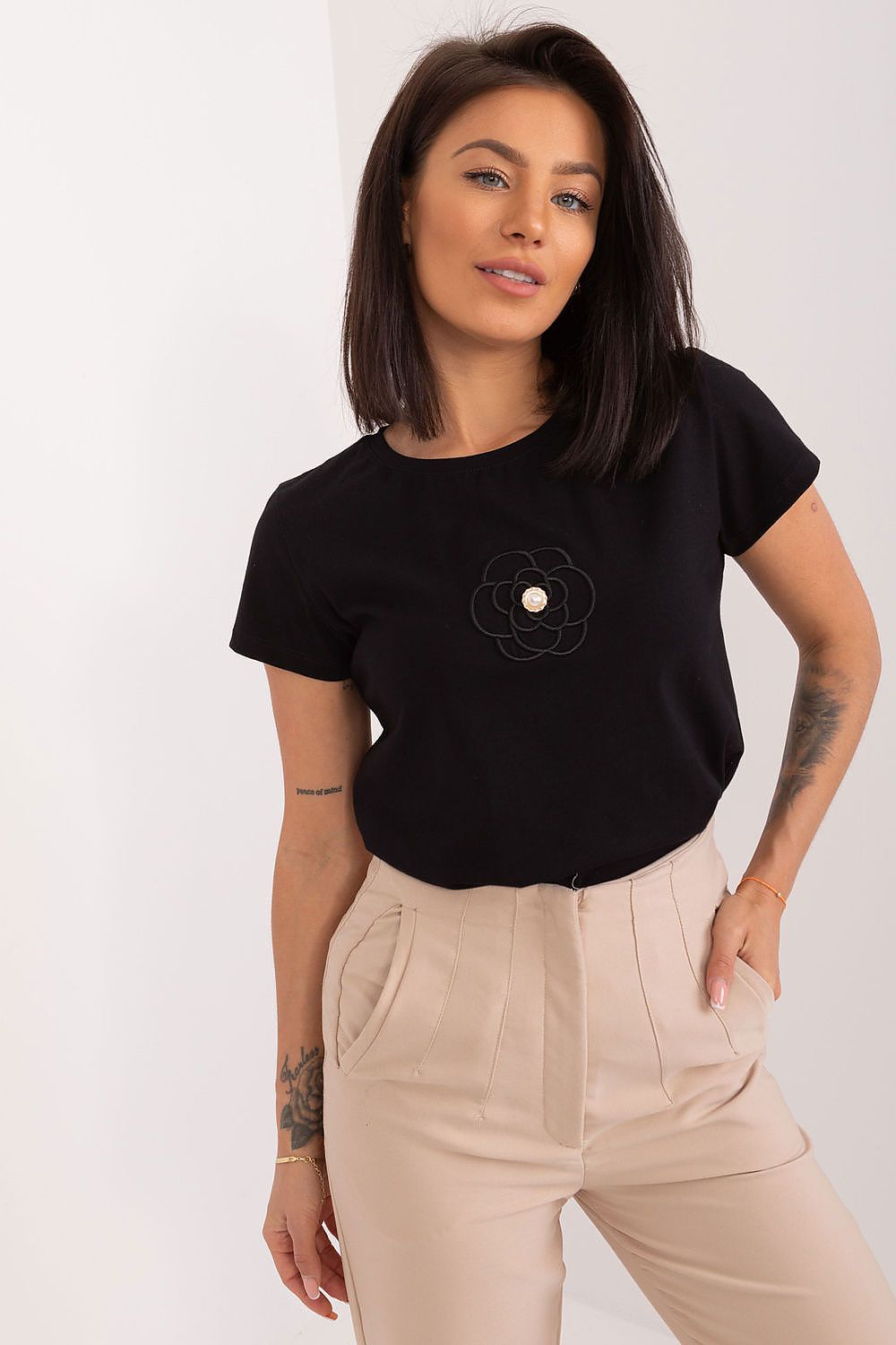 Elegant black short sleeve cotton blouse featuring an embroidered flower detail and zircon accents, styled by BFG. Model showcases the versatile round neckline and relaxed fit.