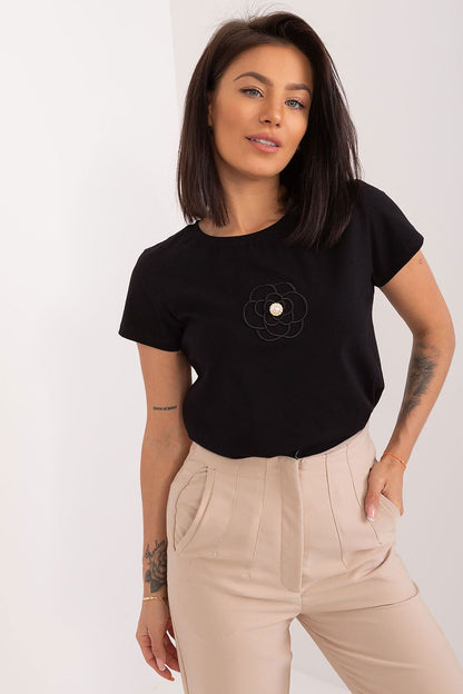Elegant black short sleeve cotton blouse featuring an embroidered flower detail and zircon accents, styled by BFG. Model showcases the versatile round neckline and relaxed fit.
