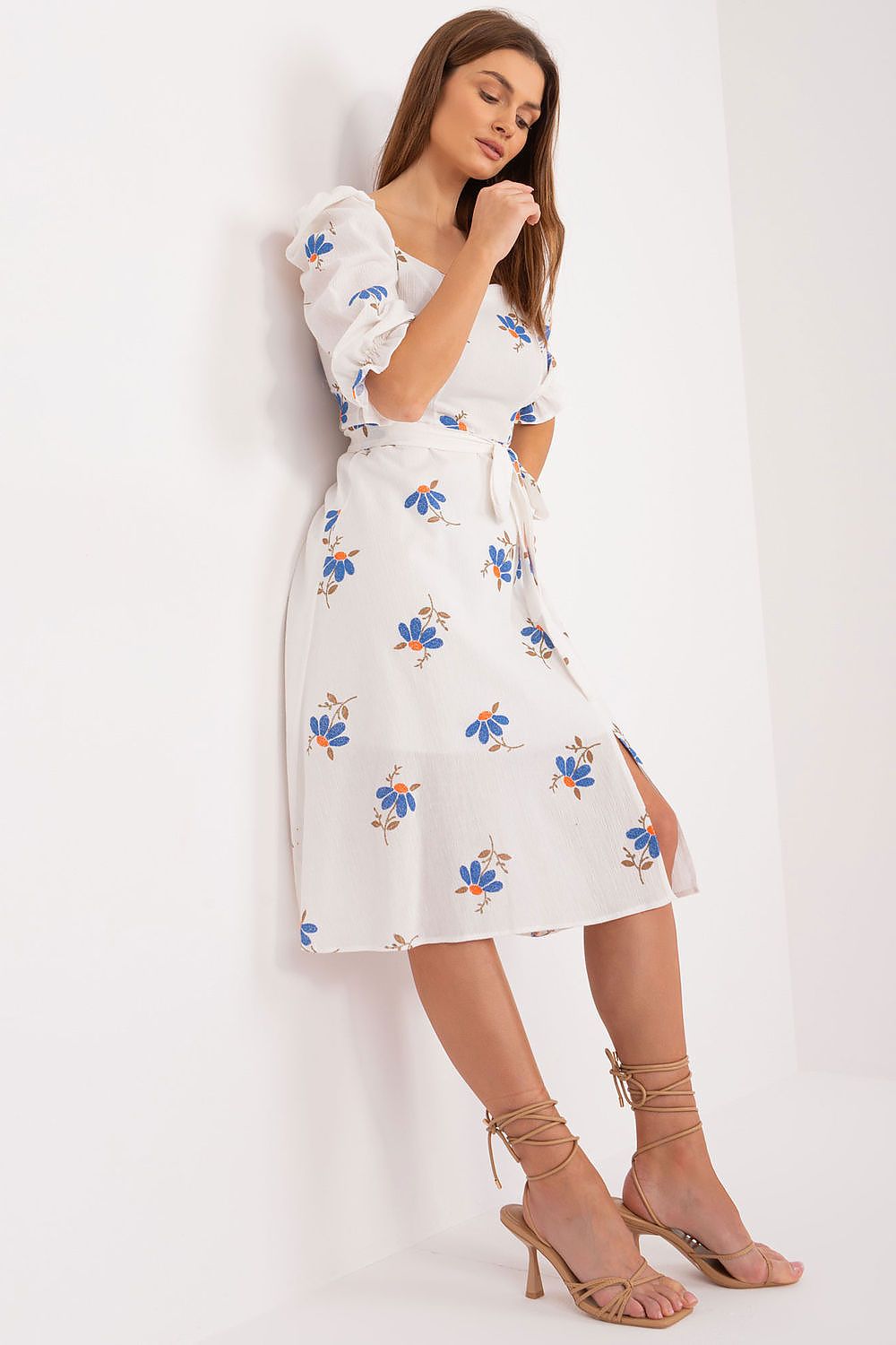 Sophisticated floral midi summer dress by Lakerta, featuring delicate ruffle sleeves and a centre slit. The model poses thoughtfully, showcasing the elegant design and soft blue floral patterns.