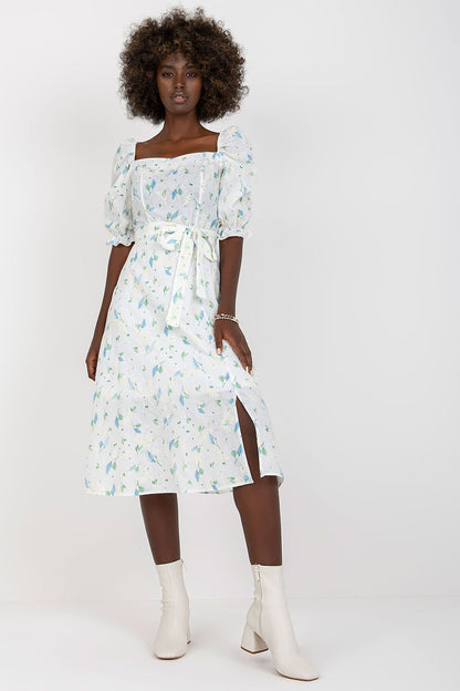 Front view of the Lakerta floral midi summer dress highlighting its elegant design with a side slit and ruffle sleeves, styled with fashionable white ankle boots.