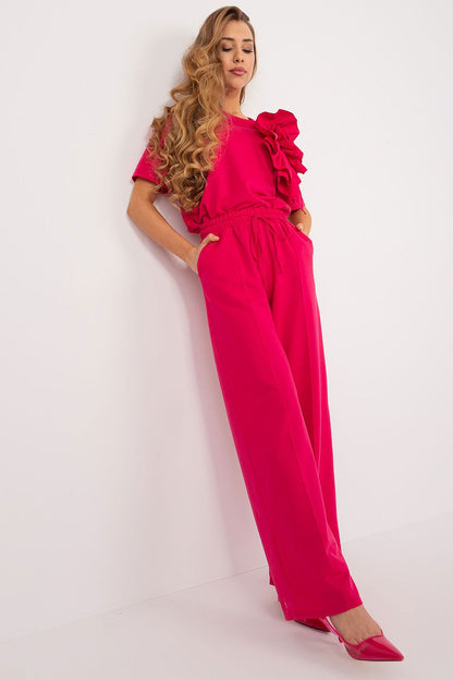 Chic model showcasing Lakerta high rise cotton blend trousers in bright pink, effortlessly paired with a floral top, ideal for elegant casual wear.