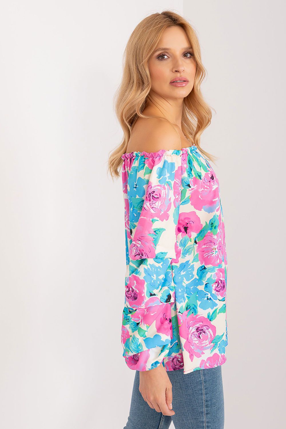 Side view of a stunning model in a floral print blouse by Rue Paris, featuring a beautiful off-the-shoulder design and vibrant floral patterns in shades of blue and pink, epitomising effortless summer elegance.