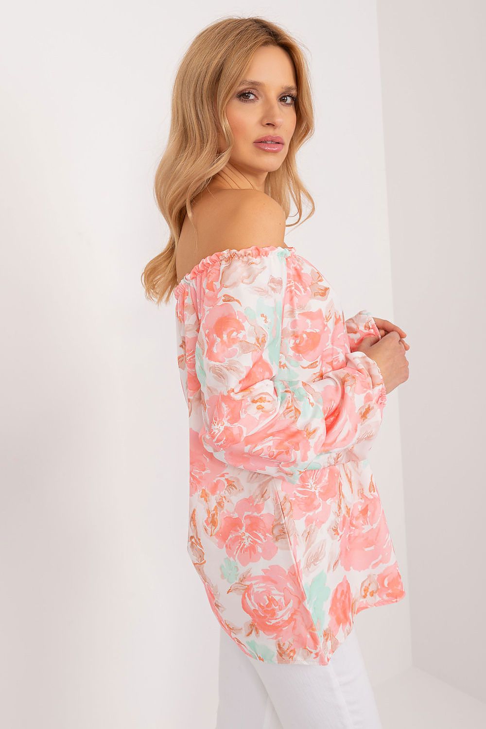 Graceful side view of a model wearing a pastel floral blouse by Rue Paris, featuring a soft off-the-shoulder style and charming floral patterns in peach and mint, ideal for sophisticated summer outings.