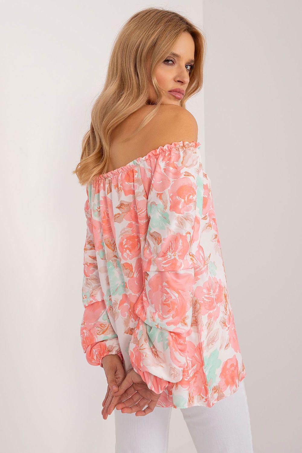 Elegant floral print blouse by Rue Paris, showcasing a Spanish neckline and long buff sleeves. The model is styled in a soft peach and mint palette, ideal for summer, exuding a luxurious charm.