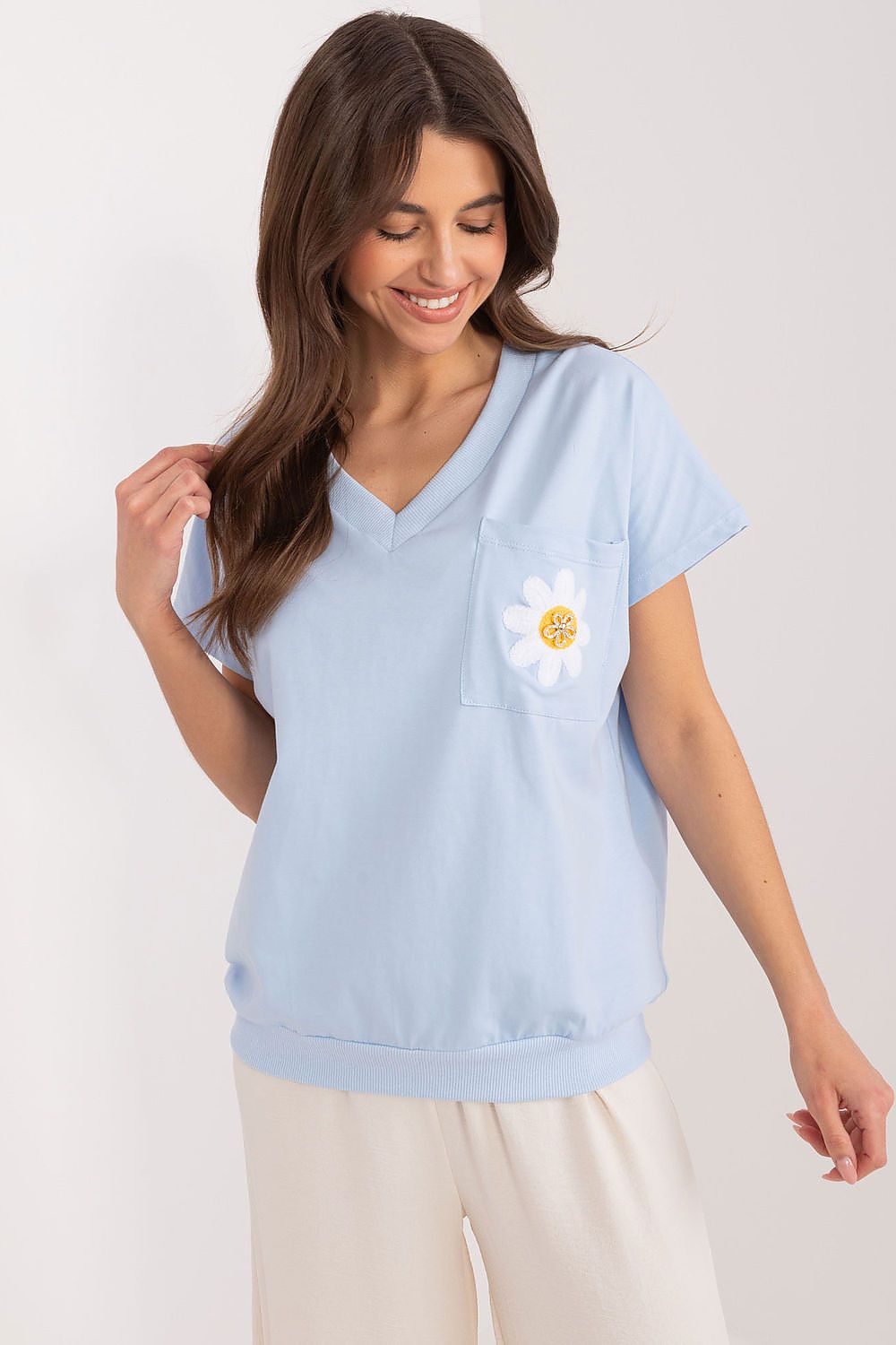 Beautiful model showcasing an elegant light blue cotton blouse with embroidered flower details and zircon accents from Rue Paris, perfect for summer casual wear.